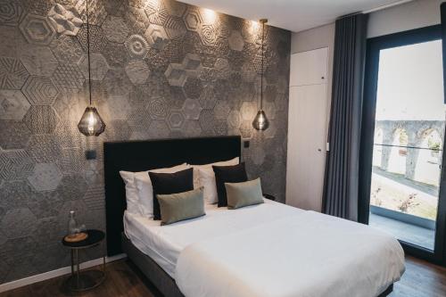 a bedroom with a large white bed with two pillows at &Tales Suites - Óbidos in Óbidos