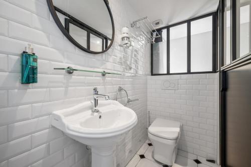 a white bathroom with a sink and a toilet at Arome Hôtel in Nice