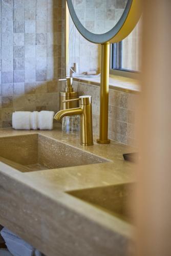 a bathroom sink with a gold faucet and a mirror at Le Rêve - Hôtel Luxe in Mesnil-Saint-Père