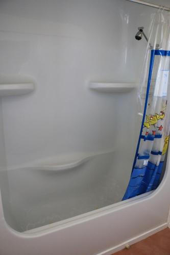 a white bath tub with a blue shower curtain at Sea'Renity Cottage in Venus Bay