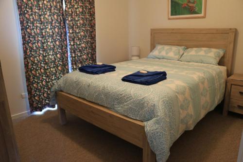 una camera da letto con un letto con due asciugamani blu sopra di Sea'Renity Cottage a Venus Bay