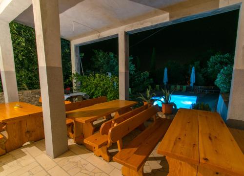 a patio with wooden tables and benches and a large window at Apartments Slavica in Dramalj