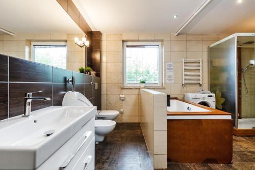 a bathroom with a sink and a toilet and a tub at Apartament Kamień LUX - sauna, wanna z hydromasażem, kominek - tuż przy jeziorze in Kamień