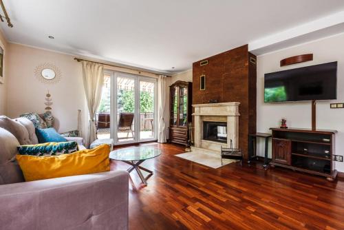 a living room with a couch and a fireplace at Apartament Kamień LUX - sauna, wanna z hydromasażem, kominek - tuż przy jeziorze in Kamień