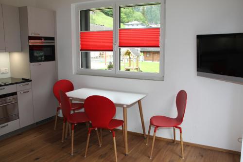 a kitchen with red chairs and a table and a window at Haus Steiner in Göschenen