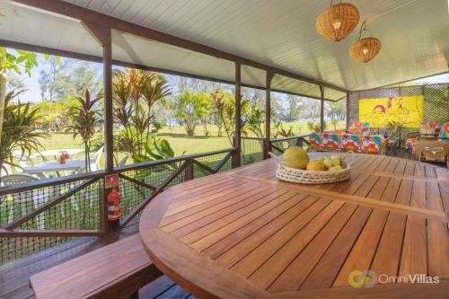 a wooden table with a bowl of fruit on a porch at Room 2 - Secluded shared Rustic Bungalow by Tipaniers Beach in Iumaru