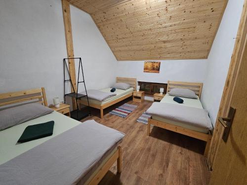 a room with three beds and a wooden ceiling at Ruralna kuća za odmor Lika in Lovinac