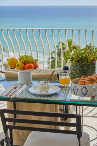 a glass table with a plate of fruit on it at Villa del Mar - "Luxurious en-suite bedroom with lounge and stunning sea view balcony in Bantry Bay" in Cape Town