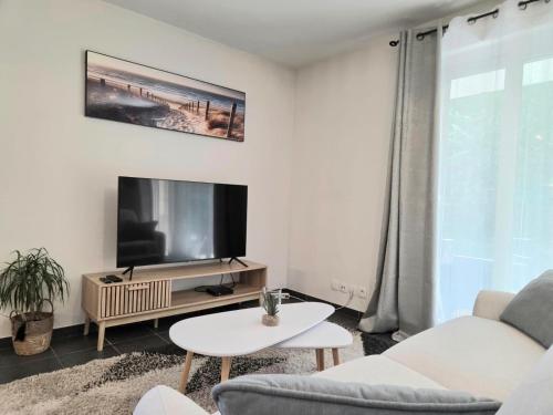 a living room with a tv and a couch and a table at Le Reposant in Thonon-les-Bains