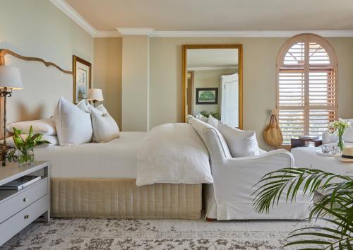 a bedroom with a white bed and two white chairs at Villa del Mar - "Luxurious en-suite bedroom with lounge and stunning sea view balcony in Bantry Bay" in Cape Town