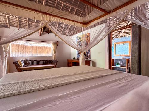 a bedroom with a large bed with a window at Beach Bohème in Paje