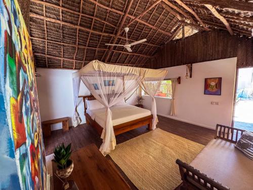 a bedroom with a bed with a mosquito net at Beach Bohème in Paje