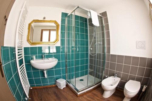 a green tiled bathroom with a sink and a toilet at Le Perine 6 in Valdobbiadene