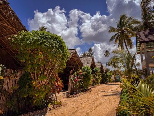 a dirt road with houses and palm trees at Beach Bohème in Paje