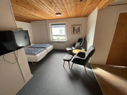 a room with a bedroom with a bed and chairs at Marskferie Tønder in Tønder
