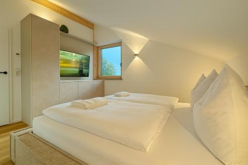 a bedroom with a large white bed with a window at Berg I Sauna I Balkon I See-Bergblick I Biohof in Rieden am Forggensee