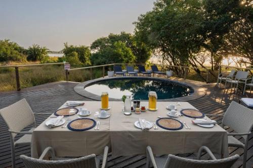 einen Tisch mit Speisen und Getränken neben einem Pool in der Unterkunft Makakatana Bay Lodge in St Lucia