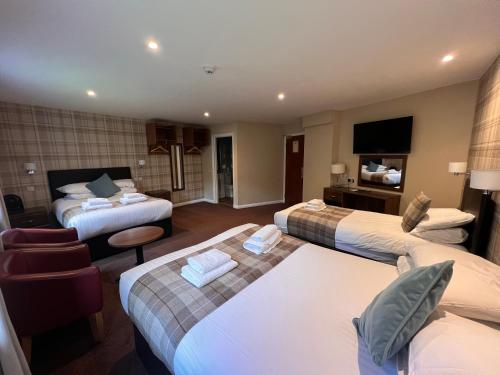 a hotel room with three beds and a television at King Robert Hotel in Stirling