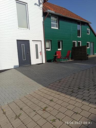 a green and white house with two chairs in front of it at Ferienwohnung Happy Life in Northeim