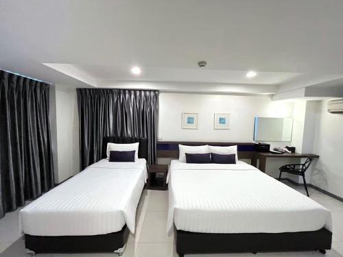 a hotel room with two beds and a desk at Cubic Pratunam in Bangkok