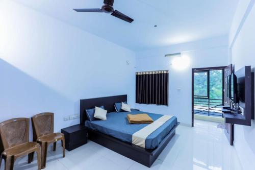 a bedroom with a bed and chairs and a tv at Igloo Residency in Vythiri