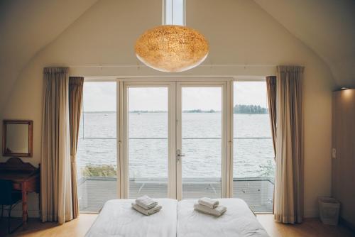 Schlafzimmer mit einem großen Fenster mit Blick auf das Wasser in der Unterkunft Meervilla Deluxe met Sauna | 8 personen - Boutique Parc Pharshoeke in Heeg