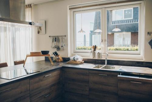 eine Küche mit Spüle und Fenster in der Unterkunft Meervilla Deluxe met Sauna | 8 personen - Boutique Parc Pharshoeke in Heeg