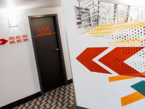 a hallway with a door and a wall with colorful paintings at ibis Styles Neckarsulm in Neckarsulm