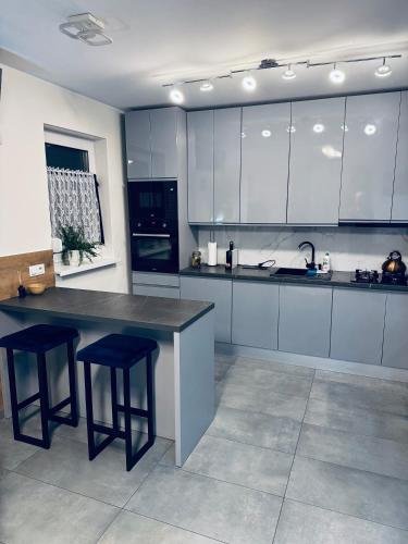 a kitchen with white cabinets and a counter and stools at Apartament Nad Nielbą in Wągrowiec