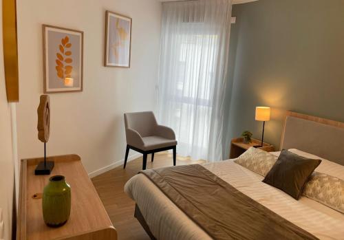 a bedroom with a bed and a chair in it at Zenao Appart'hôtels Dijon in Dijon