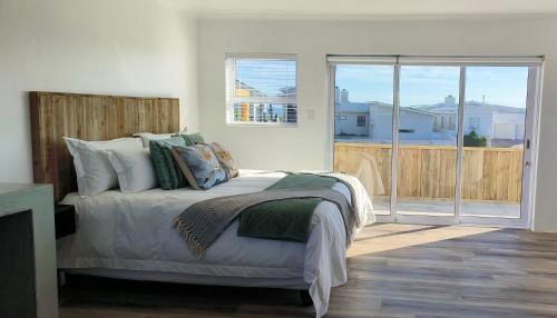 a bedroom with a bed and a sliding glass door at Audrey Hepburn Suite Yzerfontein in Yzerfontein