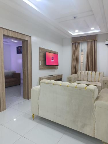 a living room with two couches and a flat screen tv at Immaculate Excellence Luxury Hotel in Owerri