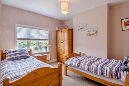 Un dormitorio con dos camas y una ventana. en Salty Dog, en Mundesley