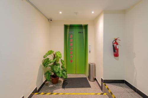 a green door in a hallway with a potted plant at Hotel Sunjoy9 OKR in Kuala Lumpur