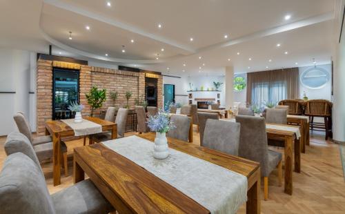 a dining room with tables and chairs and a room with a fireplace at Lotus Therme Hotel & Spa in Hévíz