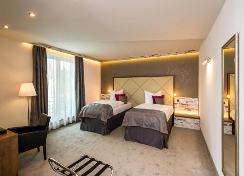 una habitación de hotel con 2 camas y una silla en Hotel Allegro en Halberstadt