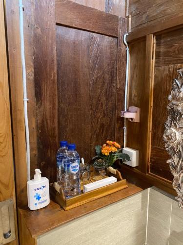a shelf with bottles of water and flowers in a bathroom at Kubu Sakian Villa and Restaurant Sidemen in Silebeng