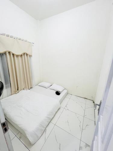 a small white room with a bed in it at Jhuna Komodo Homestay in Komodo