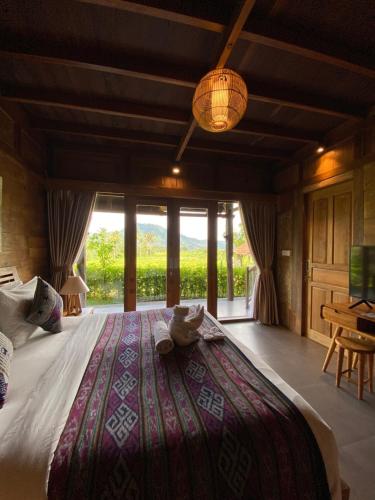 a bedroom with a large bed with a large window at Kubu Sakian Villa and Restaurant Sidemen in Silebeng