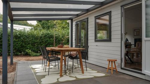 eine Terrasse mit einem Holztisch und Stühlen in der Unterkunft Boshuisje met kachel "Huisje van Loof" op de Veluwe in Nunspeet