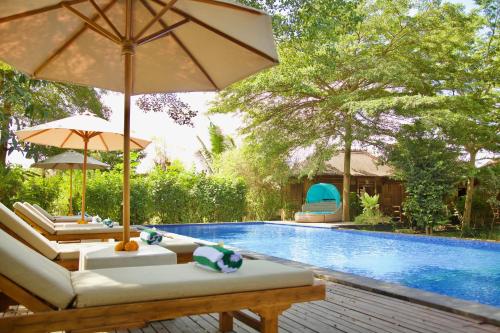 a swimming pool with two lounge chairs and an umbrella at Ardan Maison The Garden Villas in Ubud