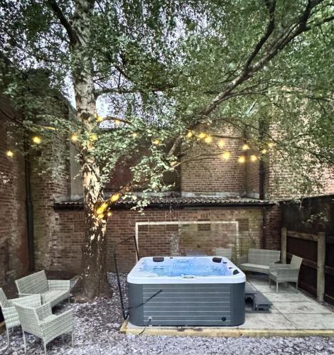 a hot tub in a yard with a tree and lights at The Secret Garden Retreat With Hot Tub in Manchester