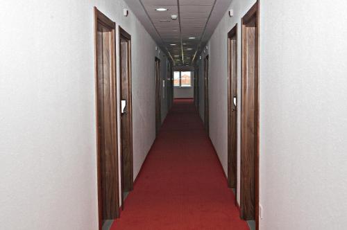 a long hallway with a red carpet and wooden doors at Hotel Serdica in Silistra