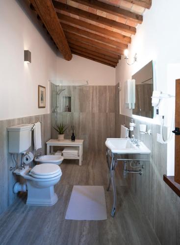 a bathroom with a toilet and two sinks in it at Tenuta La Farneta in Casole dʼElsa