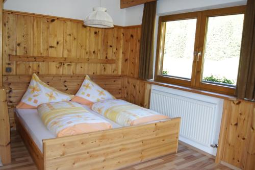 a bed in a room with wooden walls and windows at Riedhof in Mieders