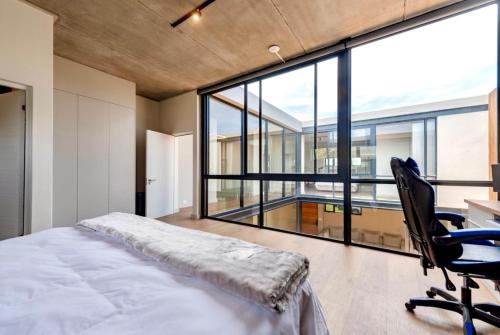 a bedroom with a bed and a desk and a large window at Keursands Luxury Beachside Holiday Escape in Keurboomstrand