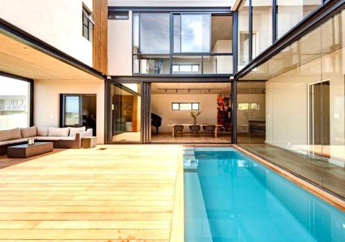 an open living room with a pool in a house at Keursands Luxury Beachside Holiday Escape in Keurboomstrand