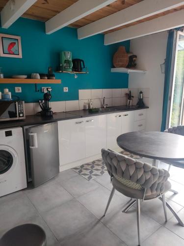 eine Küche mit einem Tisch und einer Waschmaschine in der Unterkunft La Suite 27 bis, appartement indépendant avec terrasse, proche gare et centre in Guingamp