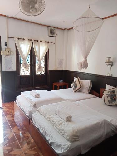 two beds in a room with two windows at Nam Ou River Lodge in Nongkhiaw