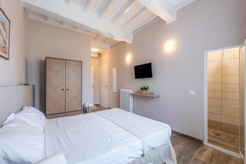 a bedroom with a white bed and a tv at L'arco del pellegrino in Monteroni dʼArbia